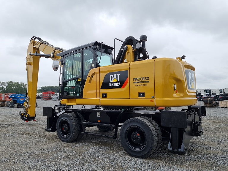 Refurbished Caterpillar MH 3024 material handling machine on solid tires with cab guards and 2-piece boom and stick with bucket linkage