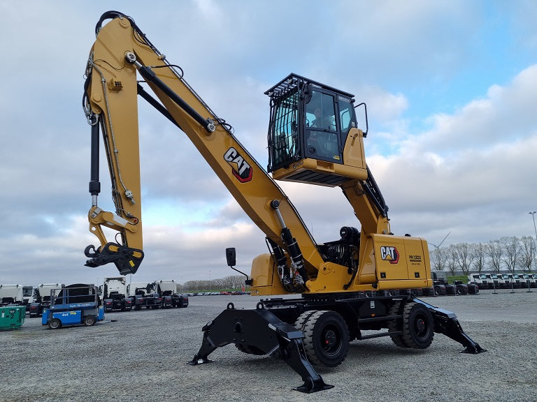Caterpillar material handler, model MH 3024, yellow and black construction equipment with a long boom and stick with bucket linkage, solid tires, parked outdoors.