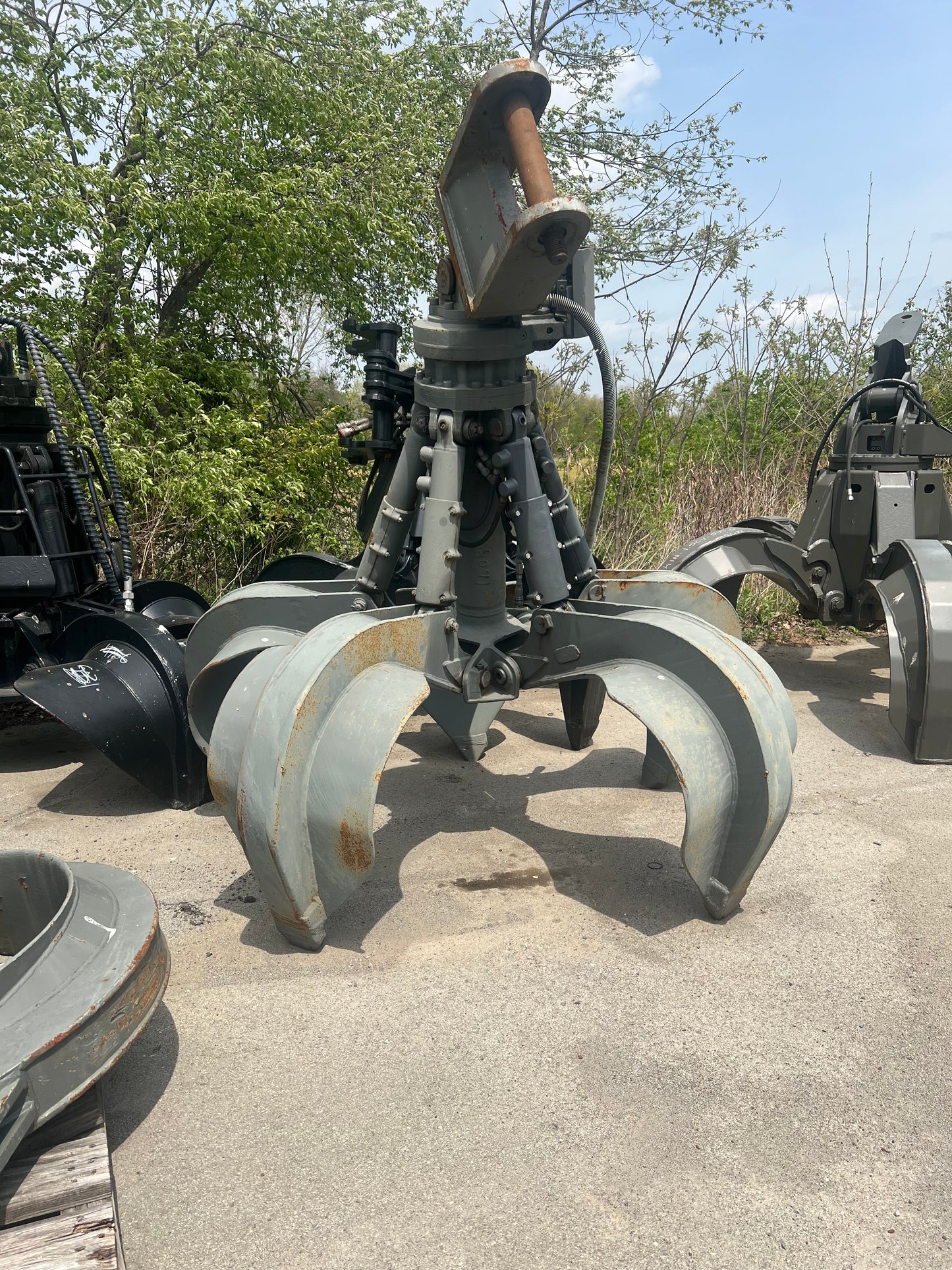 A Liebherr 5-Tine Grapple attached to a machine, primarily gray in color with black and hints of green.