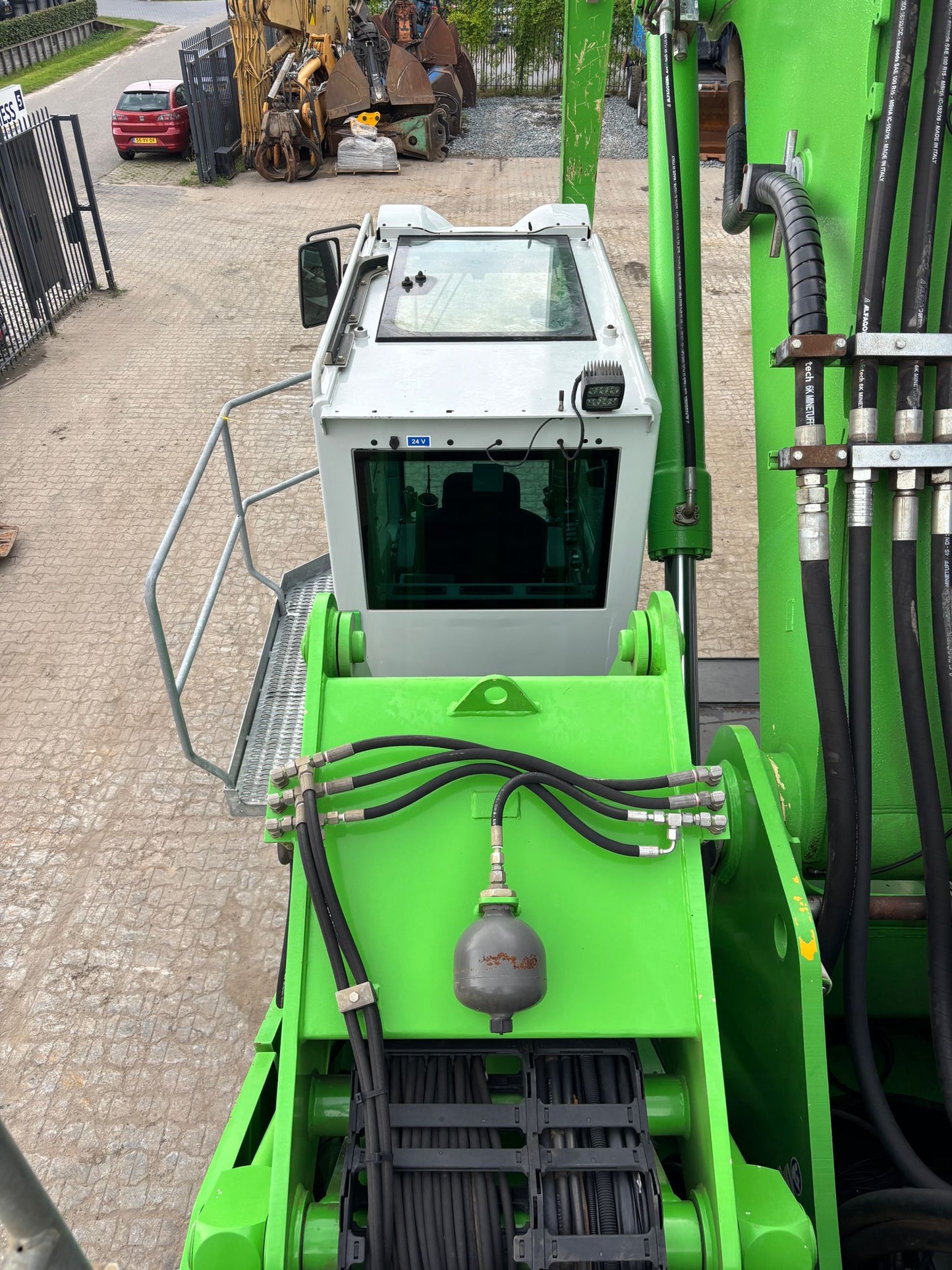 Green construction vehicle with a control cabin on a construction site