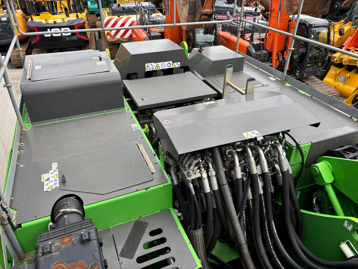 Close-up of a green Sennebogen material handler with hydraulic hoses and components